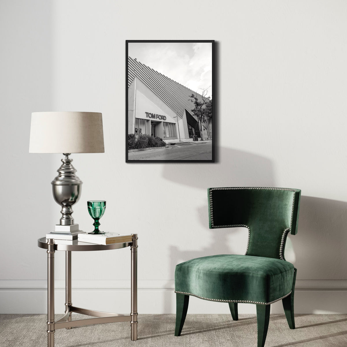 Modern living room with green velvet chair, side table, lamp, and framed black and white building poster on wall