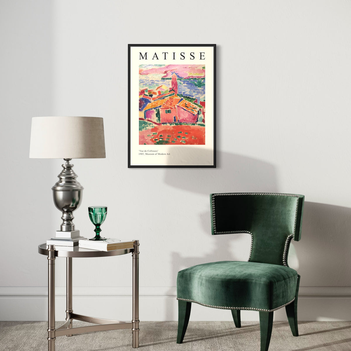 Framed Matisse art poster hanging on wall above a green velvet chair and modern side table with lamp.
