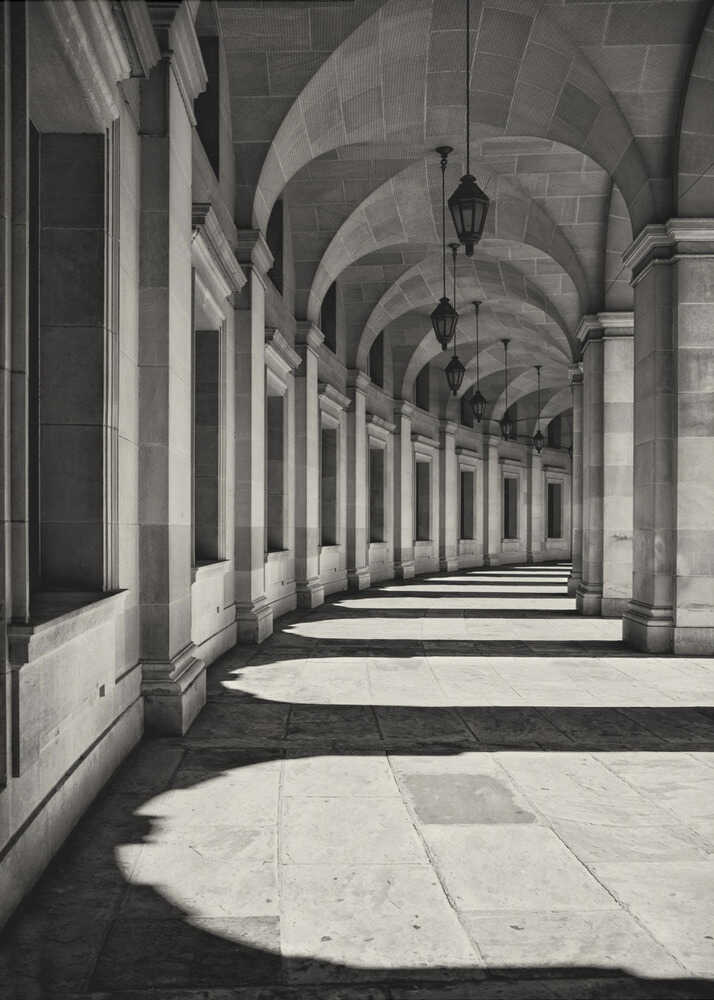 Arched colonnade poster with a black and white view of a long arched colonnade with lanterns and strong shadows