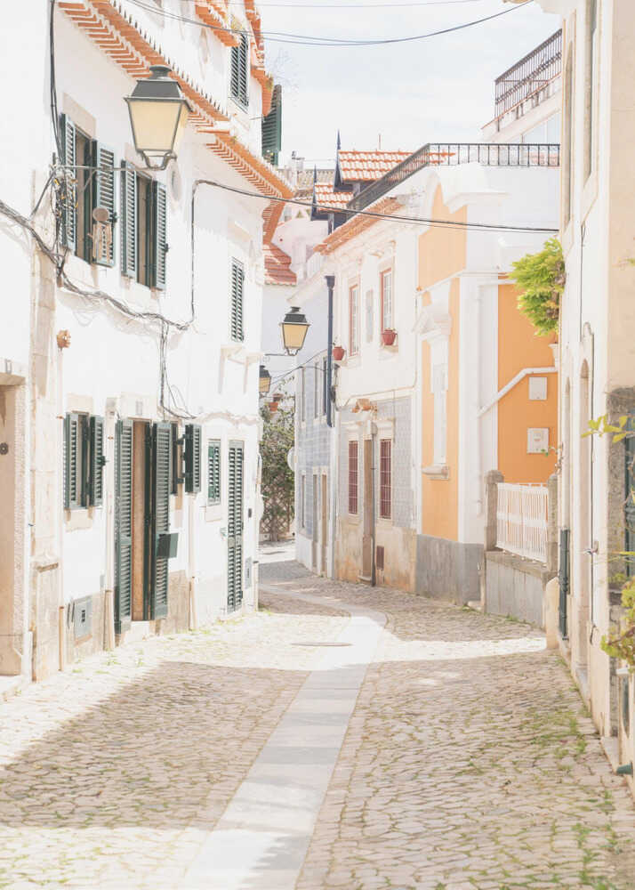 Cobblestone street poster with a narrow cobblestone street lined with white and colorful buildings