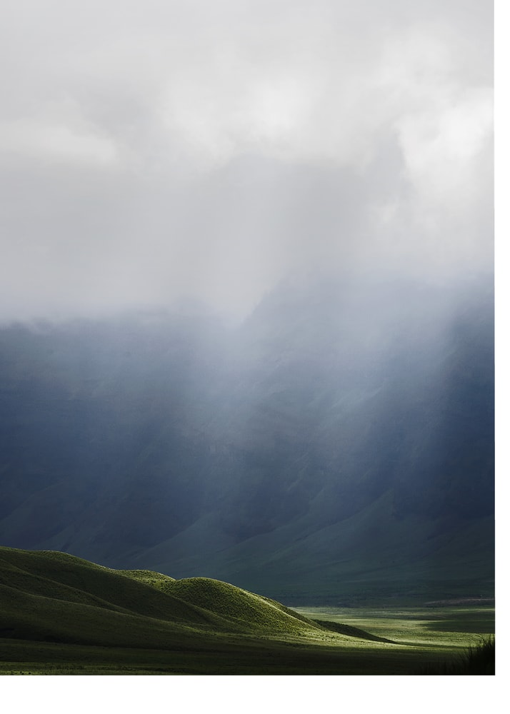 Green hills mountains poster with green rolling hills and misty mountains under clouds